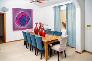 A dining area with a wooden table, blue chairs, and red vases.