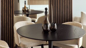 Ein moderner Essbereich mit einem runden Tisch, beigen Stühlen und einer dekorativen Vase.