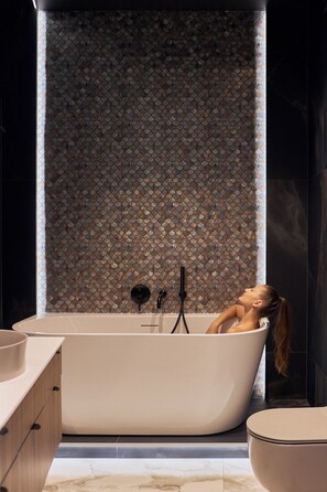 Ein modernes Badezimmer mit einer freistehenden Badewanne, einem Marmorboden und einer strukturierten Wand.