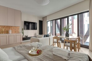 Une chambre d’hôtel moderne dotée d’un grand lit, d’un coin repas, d’une télévision et offrant une vue sur la ville.