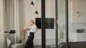 Ein modernes Wohnzimmer mit einem großen Flachbildfernseher, einer Couch, einem gemusterten Sessel und einem Couchtisch.