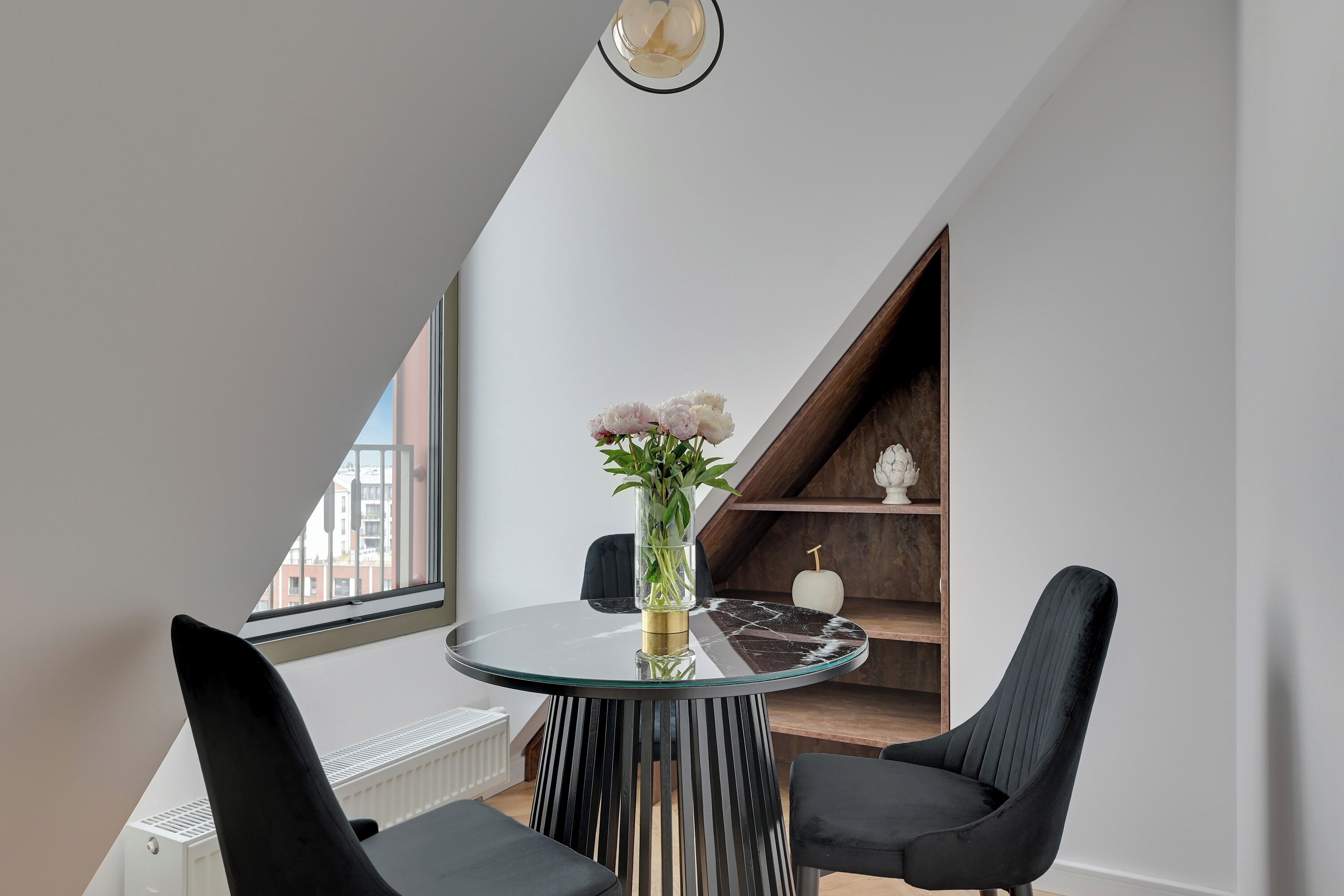 A modern dining area with a glass table, black chairs, and a vase with flowers.