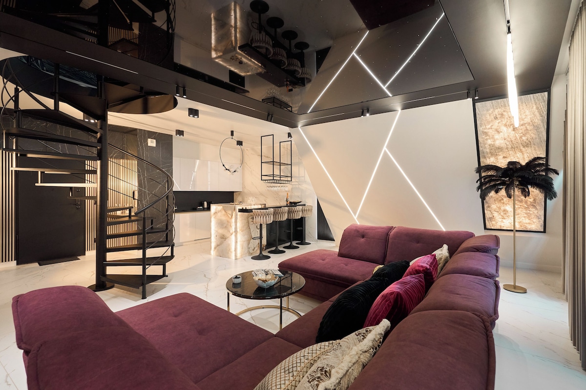 A modern living room with a sofa, a coffee table, and a kitchen in the background.
