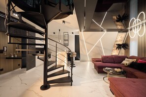 A modern interior with a spiral staircase, a red sofa, and a geometric light installation. - Granaria Premium Suites by Downtown Apartments (Gdańsk)
