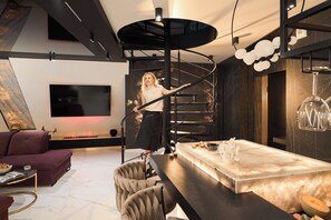 A modern interior with a spiral staircase, a flat-screen TV, a dining area with a marble table, and a sofa. - Granaria Premium Suites by Downtown Apartments (Gdańsk)