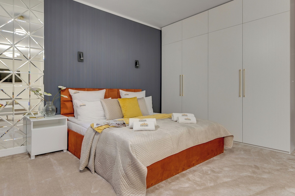 A modern bedroom with a bed, nightstands, a wardrobe, and decorative elements.