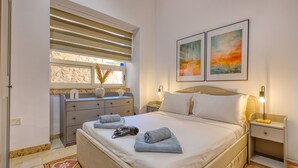 A neatly arranged bedroom with a bed, bedside tables, and a window with blinds. - Charming and cosy maisonette in Sliema RABE1-1 (Sliema)