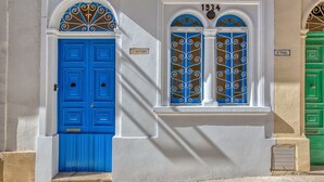 A building with a blue door and two arched windows with decorative metal grilles. - Charming and cosy maisonette in Sliema RABE1-1 (Sliema)