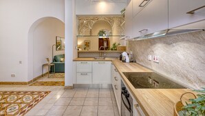 A modern kitchen with white cabinets, a glass backsplash, and a built-in oven. - Charming and cosy maisonette in Sliema RABE1-1 (Sliema)