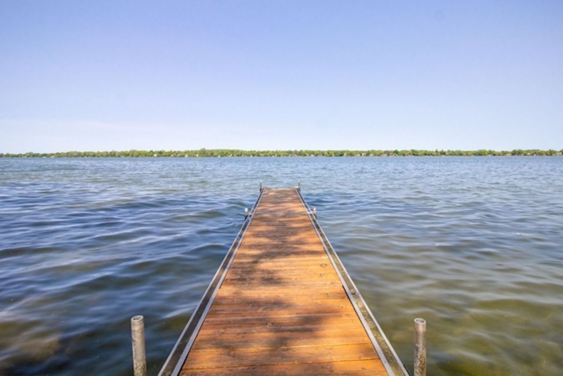 A wooden pier extending into calm water with a clear sky above.