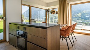 Una cocina moderna con una isla grande, horno integrado y abundante luz natural gracias a grandes ventanales.