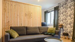 Een woonkamer met een bank, een klein rond tafeltje, een decoratief roomdivider en een behang met patroon.