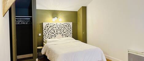 A bedroom with a bed, a wardrobe, a hanging light fixture, and a wall-mounted light.