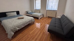 A bedroom with two single beds, a sofa, and a radiator. - AriProp Zeitz Stone Wall Apartment - 8 guests. (Zeitz)