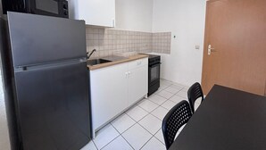 A compact kitchen with a refrigerator, stove, sink, and white cabinets. - AriProp Zeitz Stone Wall Apartment - 8 guests. (Zeitz)