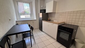 A compact kitchen with a dining table, chairs, a stove, and a window with a view. - AriProp Zeitz Stone Wall Apartment - 8 guests. (Zeitz)