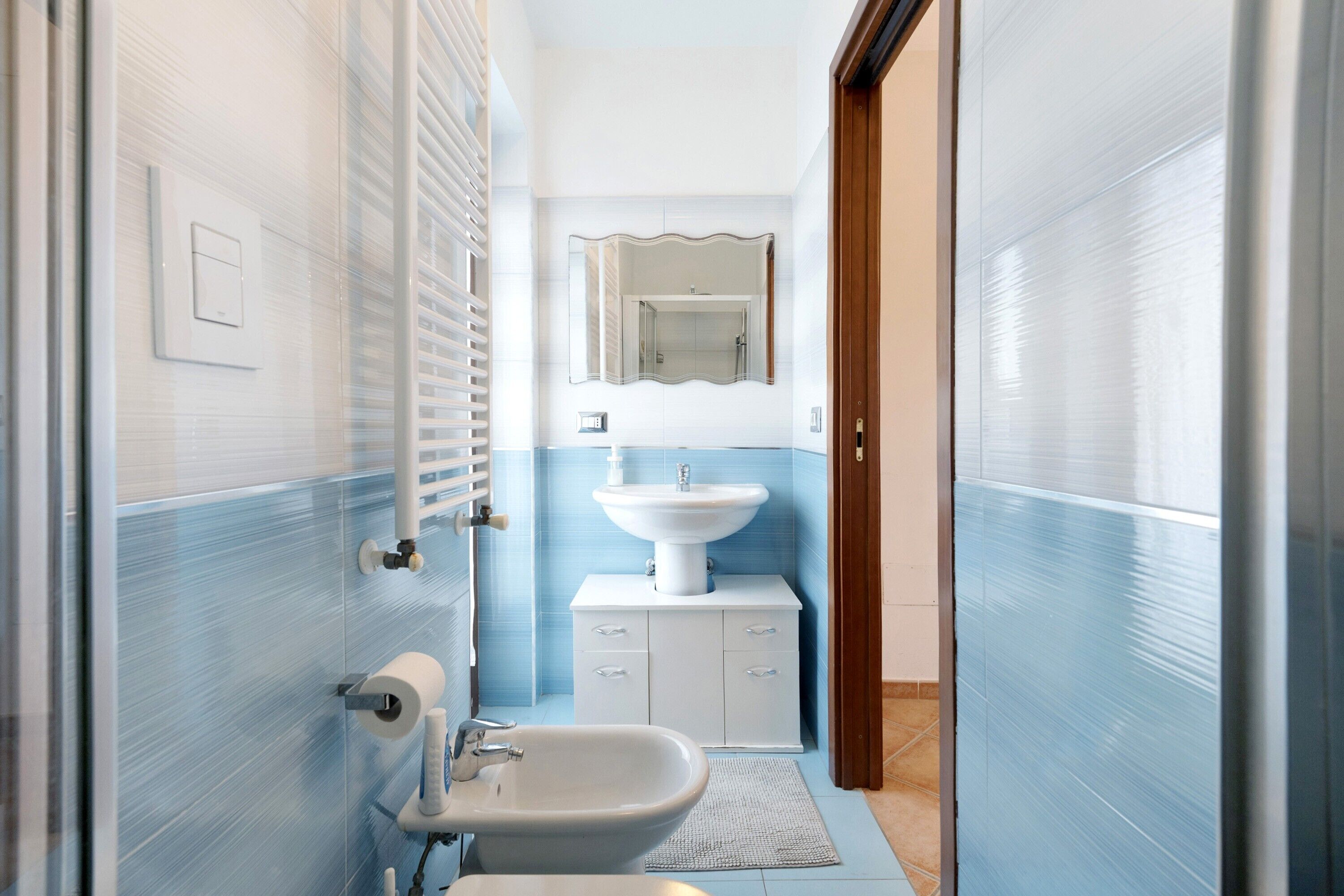 A bathroom with a white sink, a mirror, and a toilet.