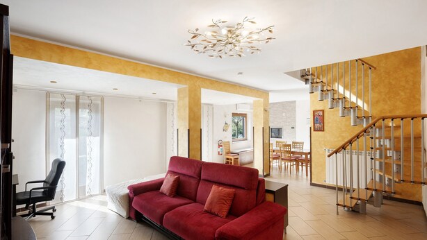 A modern living room with a red sofa, a dining area, and a staircase. - Villa 'Relax' with Mountain View, Wi-Fi and Air Conditioning (Ruviano)