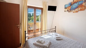 A bedroom with a bed, a television, and a balcony with a view. - Villa 'Relax' with Mountain View, Wi-Fi and Air Conditioning (Ruviano)