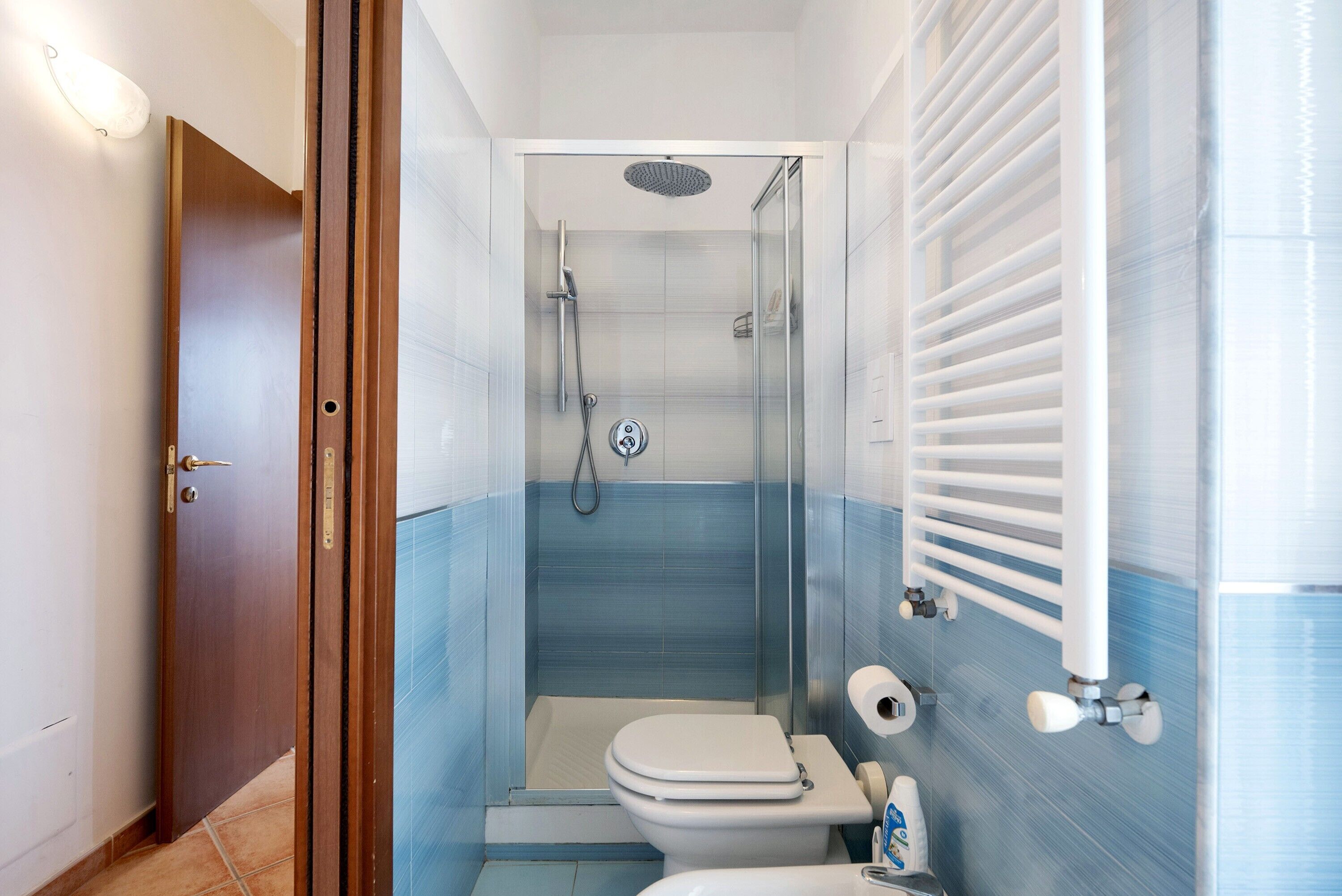 Un baño con ducha, inodoro y perchero para toallas.