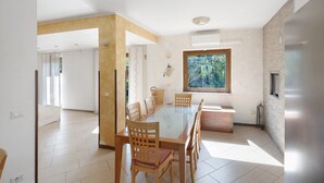 A spacious dining area with a long table, wooden chairs, and a large window with a view of greenery. - Villa 'Relax' with Mountain View, Wi-Fi and Air Conditioning (Ruviano)