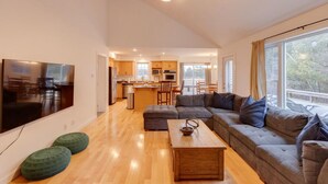 A modern living room with a large sectional sofa, a wooden coffee table, and a flat-screen TV mounted on the wall. - Cozy 4 bedroom house for rent in the heart of the Mountains.  Minutes to Cannon. (Franconia)