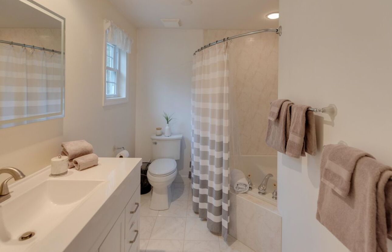 Un baño con lavamanos blanco, inodoro y zona de ducha.
