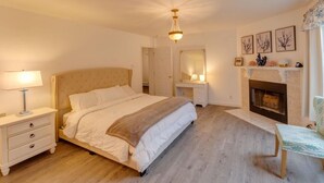 A bedroom with a large bed, bedside tables, a mirror, a fireplace, and a bench. - Cozy 4 bedroom house for rent in the heart of the Mountains.  Minutes to Cannon. (Franconia)