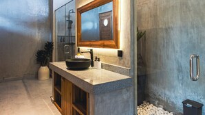 Ein modernes Badezimmer mit einem großen Spiegel, einem schwarzen Waschbecken und einer Duschkabine.