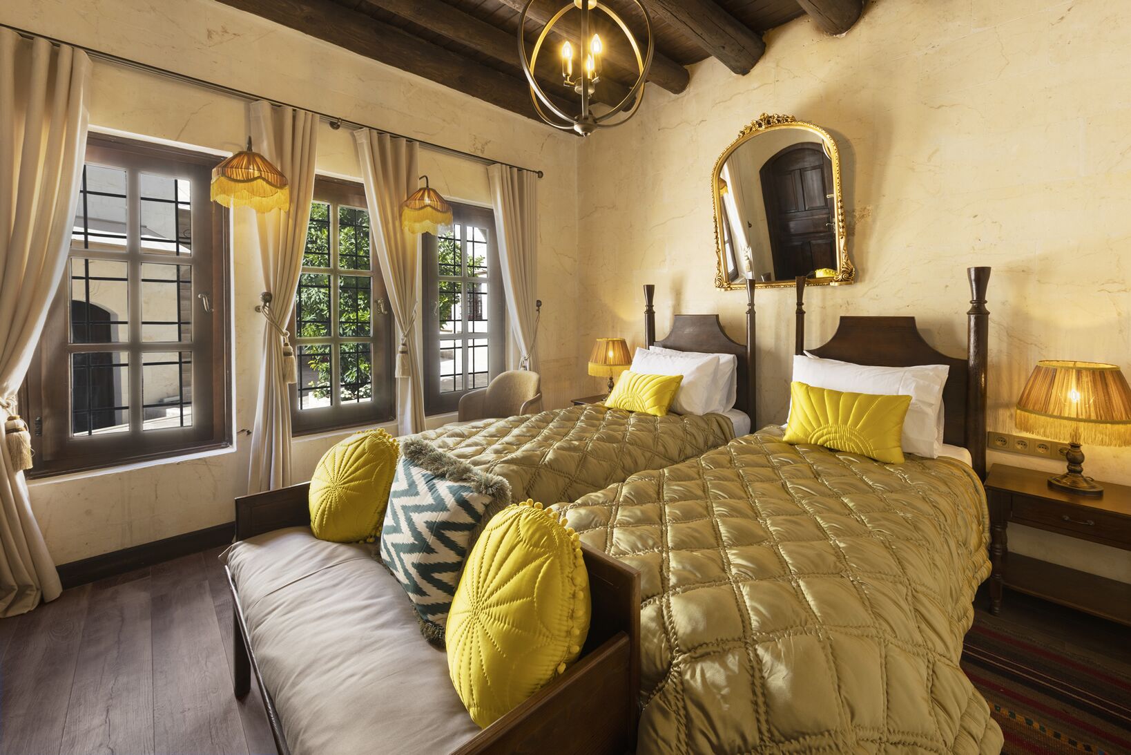 A double room with two beds, a large mirror, and a chandelier.