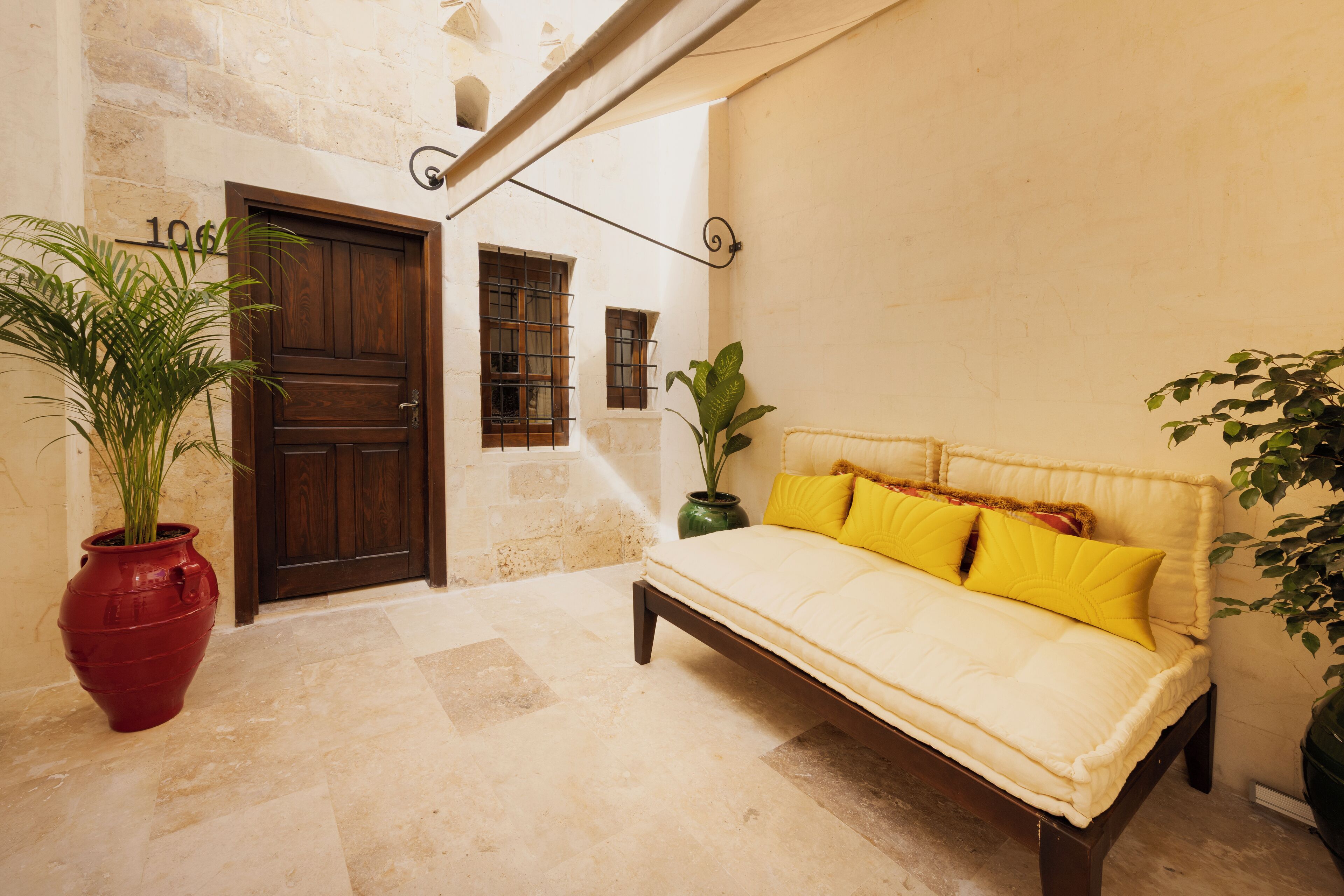 A cozy room with a bed, a potted plant, and a door.