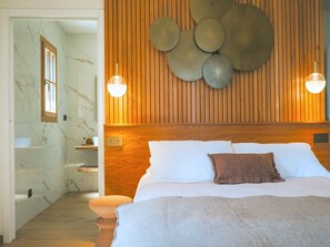 A bedroom with a wooden headboard, a bed with white and brown bedding, and a wall-mounted circular light fixture.