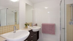 Une salle de bain avec deux lavabos, un miroir et une douche en verre.