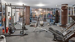 Une salle de sport équipée de divers appareils d’exercice, d’un tapis de course et d’un sac de frappe.