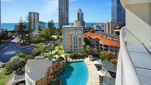 Un hôtel doté d’une piscine, offrant une vue sur la ville et donnant sur une plage en arrière-plan.