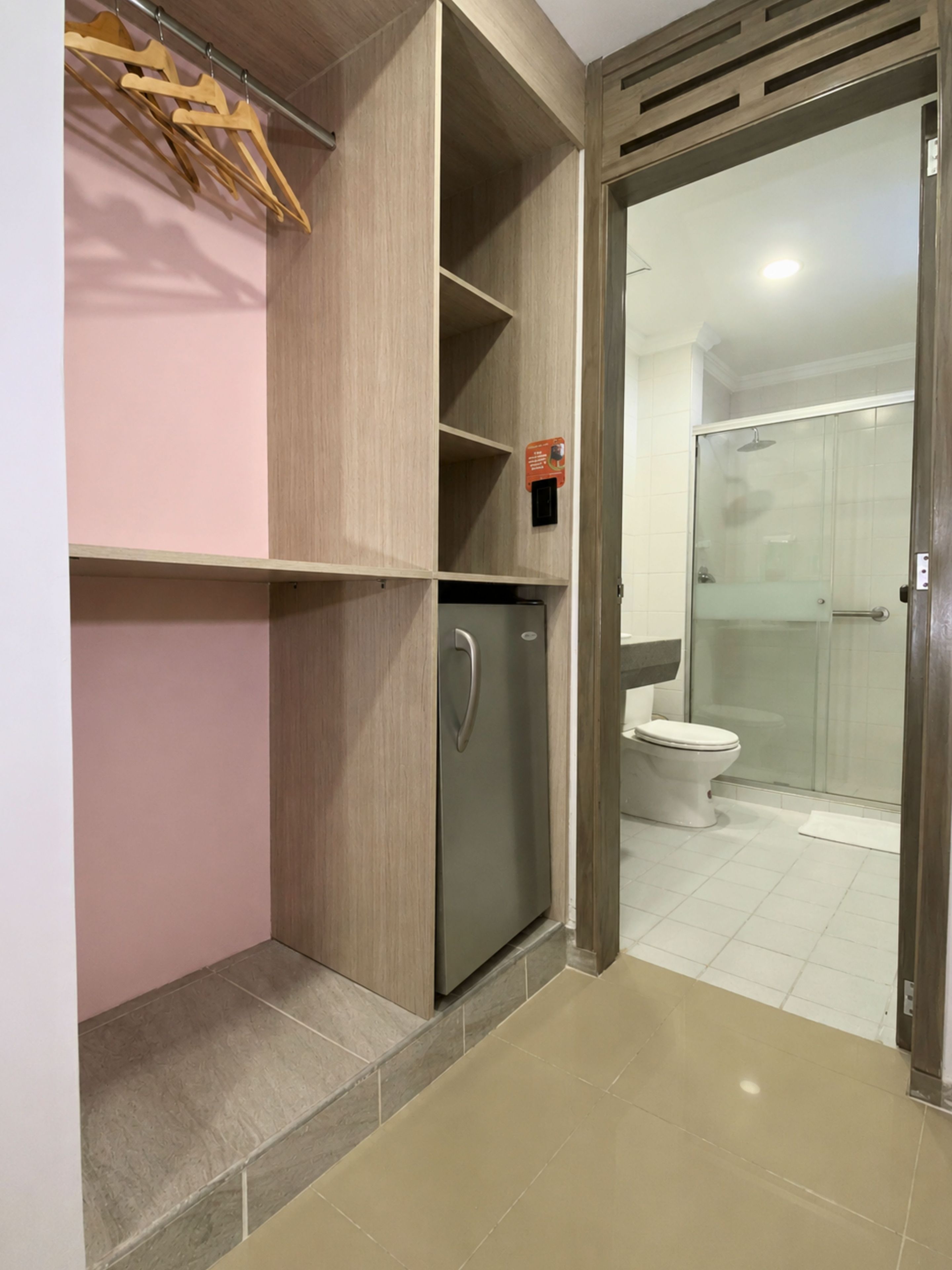 A bathroom with a shower, toilet, and a built-in refrigerator.