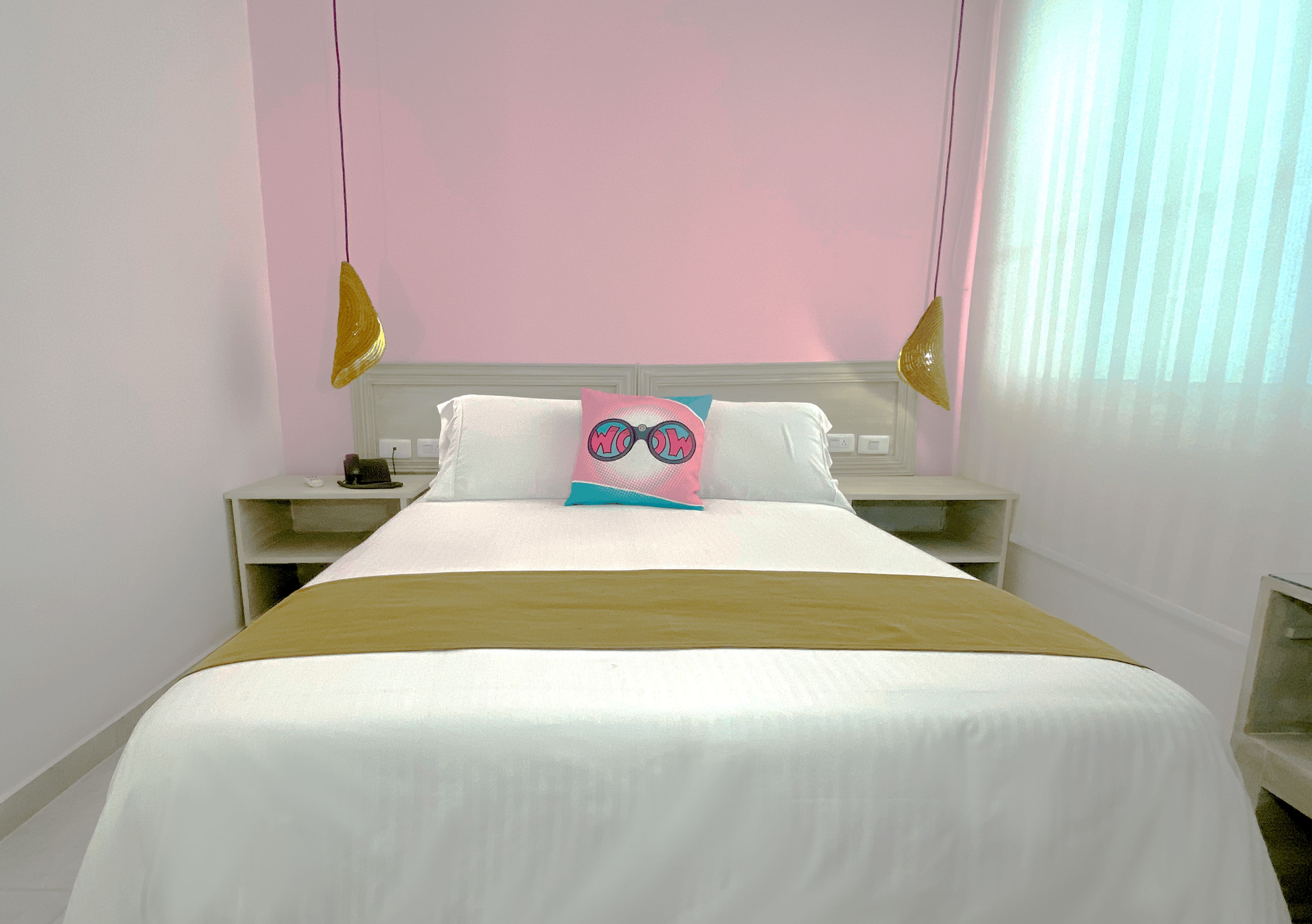 Habitación de hotel con cama, mesita de noche y ventana con persianas.