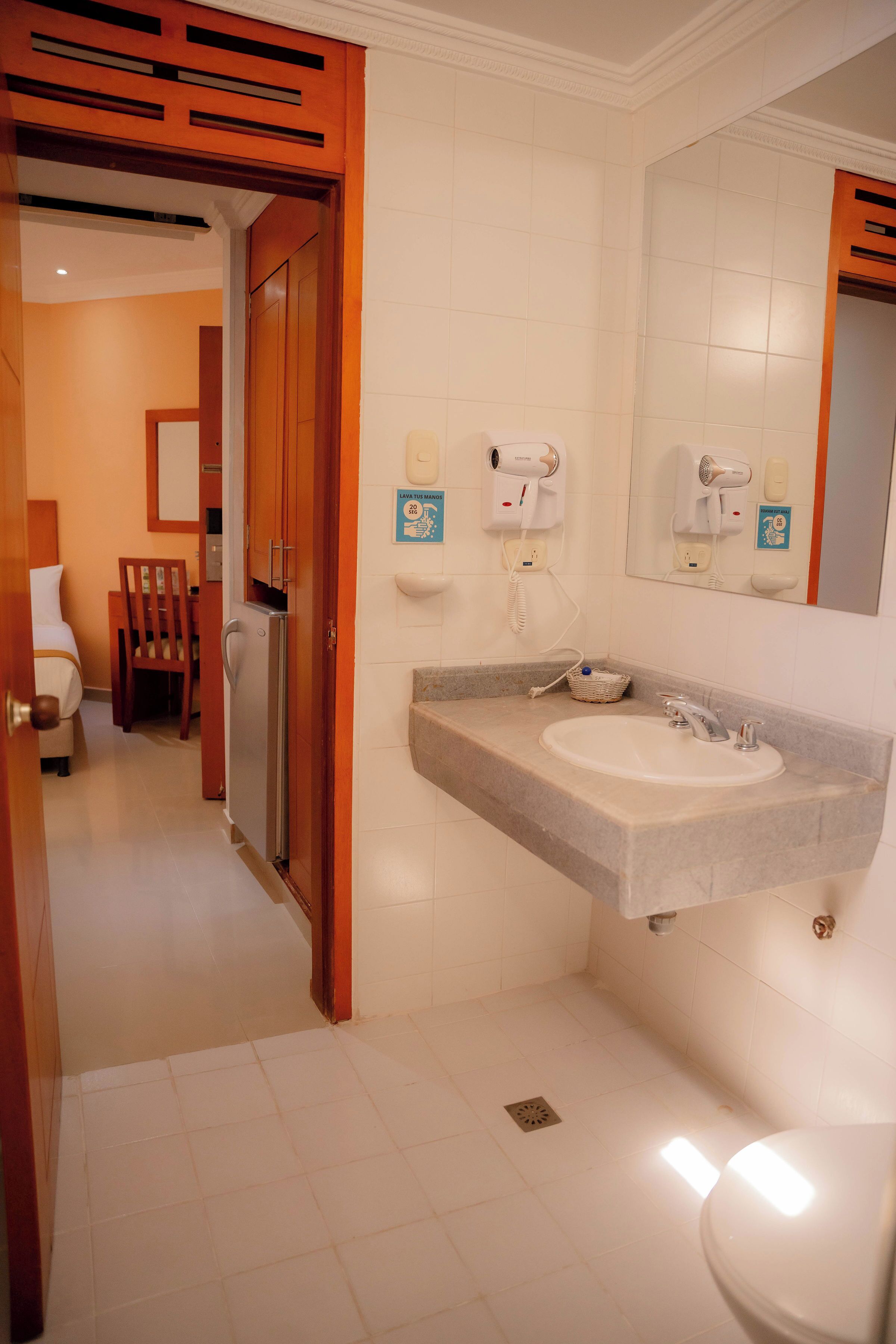 Un baño de hotel con lavamanos, espejo y perchero para toallas.