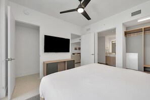 A bedroom with a bed, a ceiling fan, a TV, and a walk-in closet.