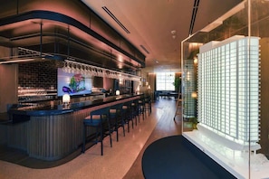 A modern bar area with a curved counter, bar stools, and a display of wine glasses.