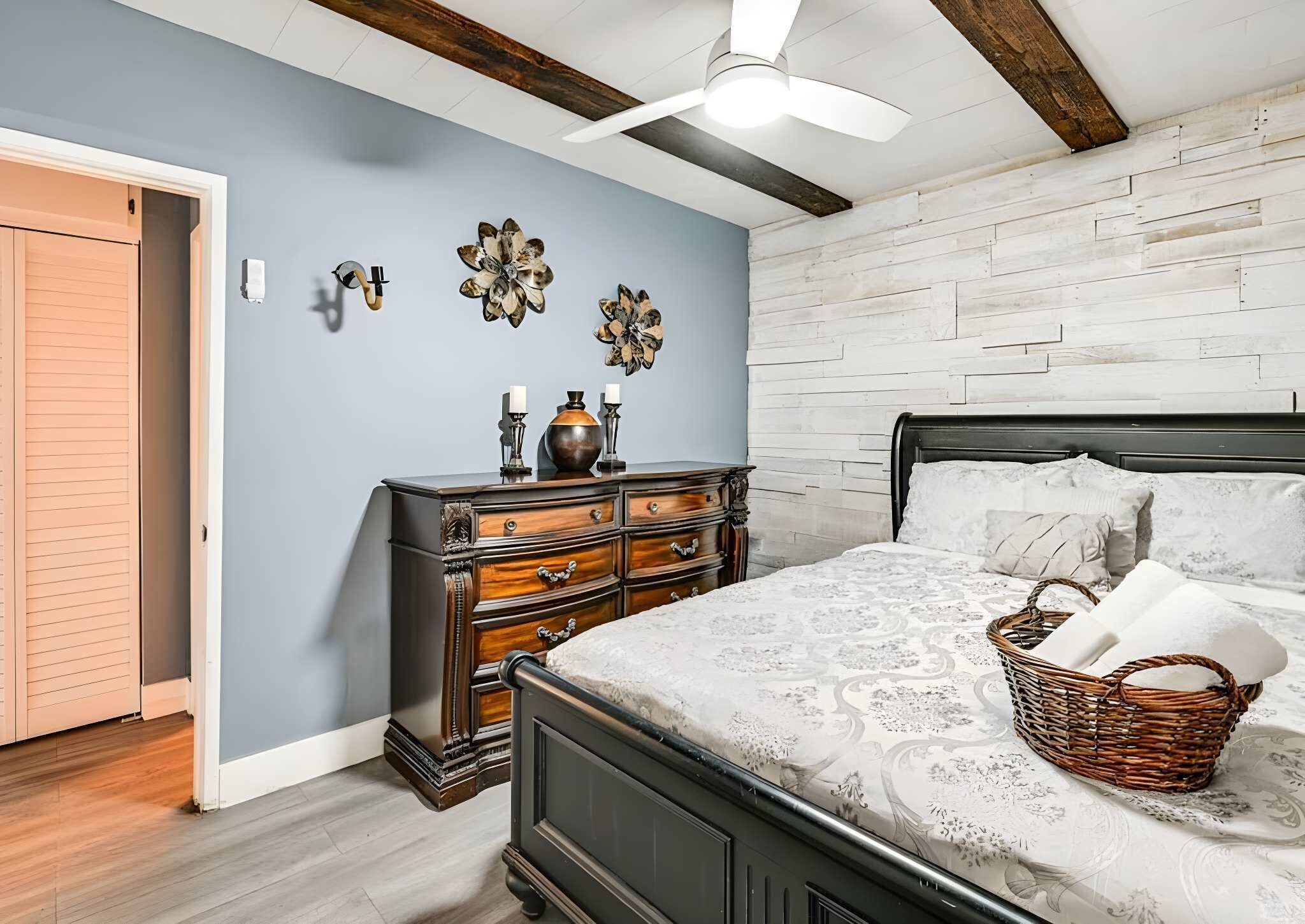 Een slaapkamer met een bed, een dressoir en decoratieve wandkunst.