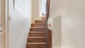 Una escalera de madera con una pared blanca y una ventana pequeña en la parte superior.