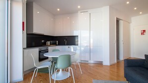 Cocina moderna con armarios blancos, encimera negra y comedor con una mesa redonda y dos sillas.