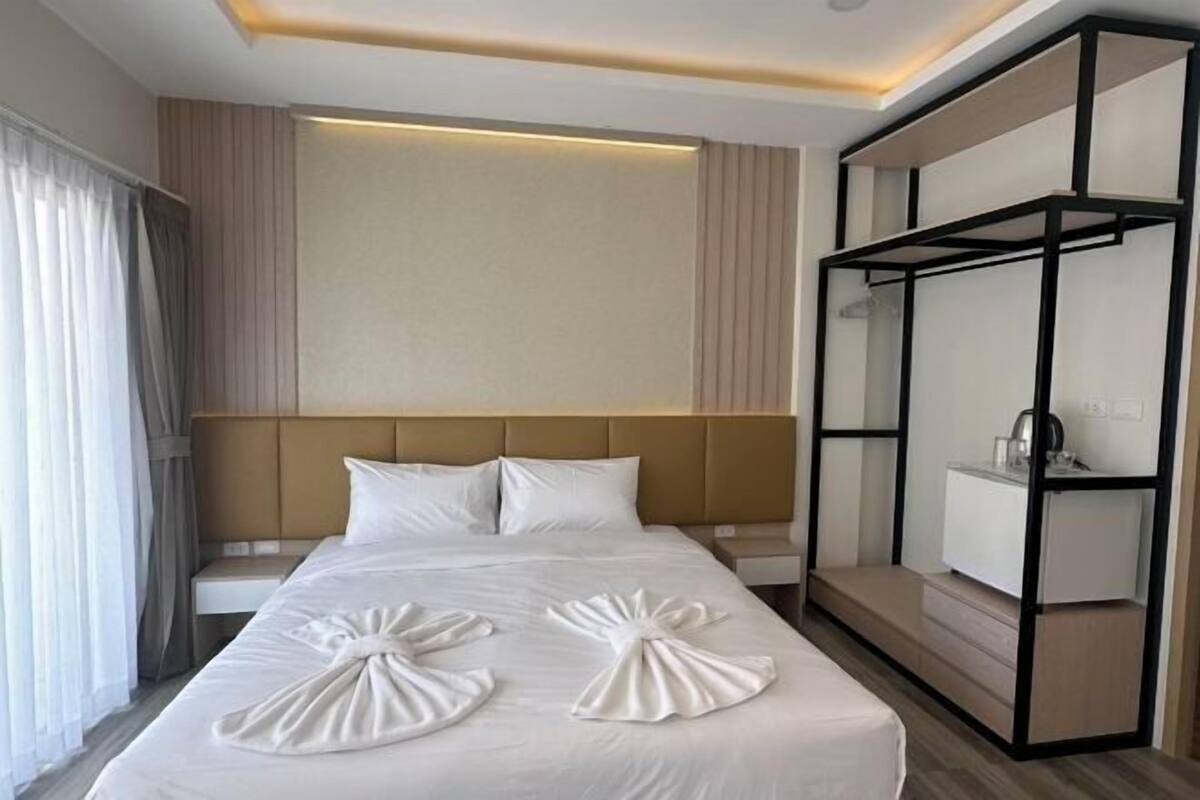 Une chambre d’hôtel comprenant un lit, des tables de chevet, une armoire et une tête de lit.