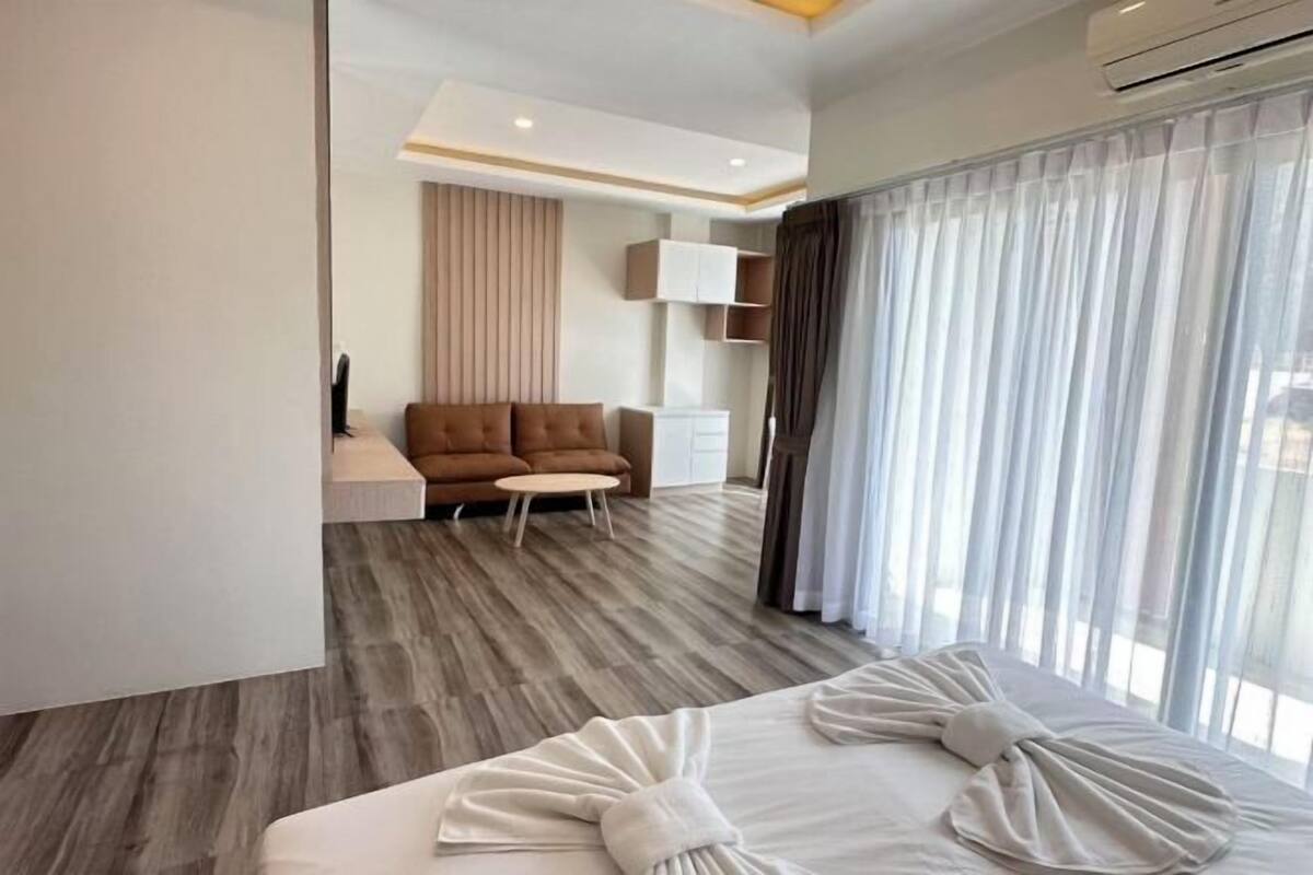 Une chambre d’hôtel moderne avec un grand lit, un canapé, une petite table et un téléviseur.