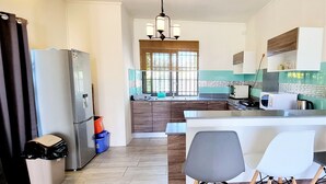 A modern kitchen with a central island, a refrigerator, a microwave, and a sink. - Royal Residence A3 - Gated Semi Detached Spacious Residence in Pereybere (Grand Baie)