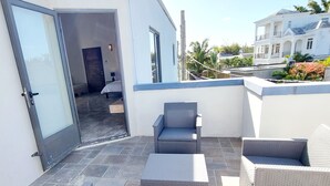 A modern outdoor patio with wicker furniture, a glass door entrance, and a view of the surrounding neighborhood. - Royal Residence A3 - Gated Semi Detached Spacious Residence in Pereybere (Grand Baie)