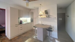 A compact kitchen with a central island, a ceiling fan, and a small bar stool.