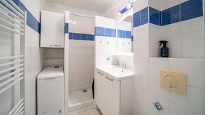 A bathroom with a shower, a toilet, a sink, and a mirror.