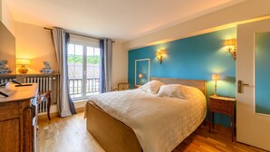 Un dormitorio con cama, mesitas de noche, cómoda y ventana con cortinas.